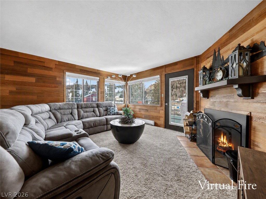 Warm wood-paneled walls frame a cozy living space complete with a fireplace and carpet flooring.