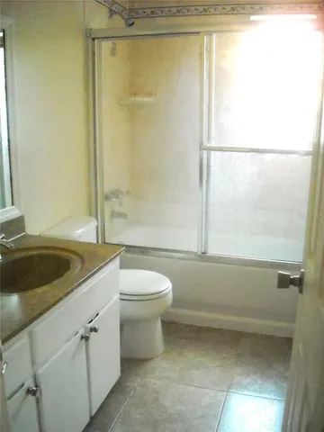 a bathroom with a granite countertop bathtub shower sink vanity and toilet