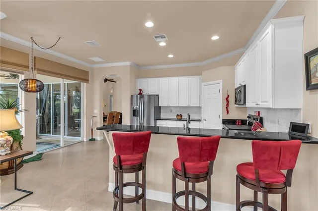a kitchen with stainless steel appliances kitchen island granite countertop a dining table chairs and a refrigerator