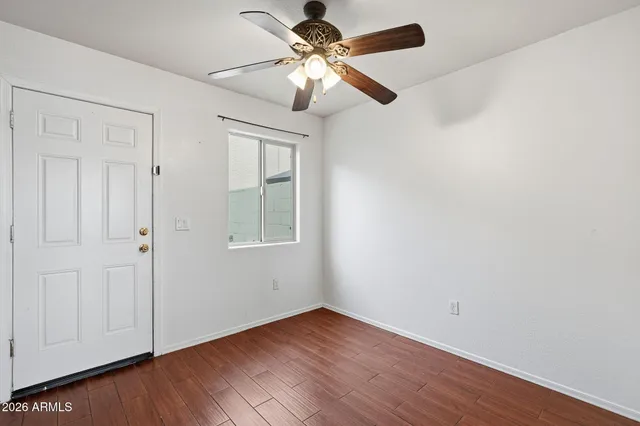 a view of an empty room with window and wooden floor