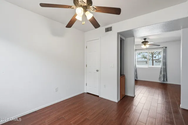 an empty room with wooden floor chandelier fan and closet area