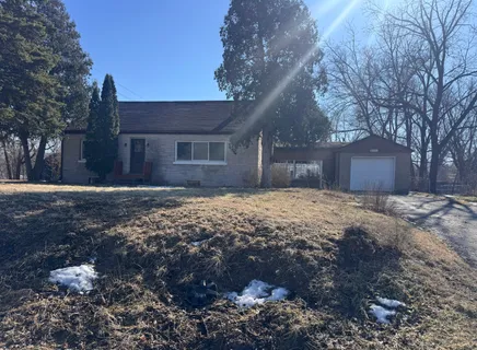a front view of a house with a yard and a large tree
