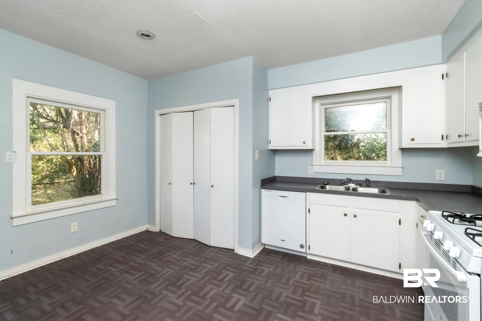 731 Jemison Street Mobile, AL 36606 - Photo 7 of 27 Kitchen featuring white appliances, dark countertops, a textured ceiling, white cabinets, and parquet flooring
