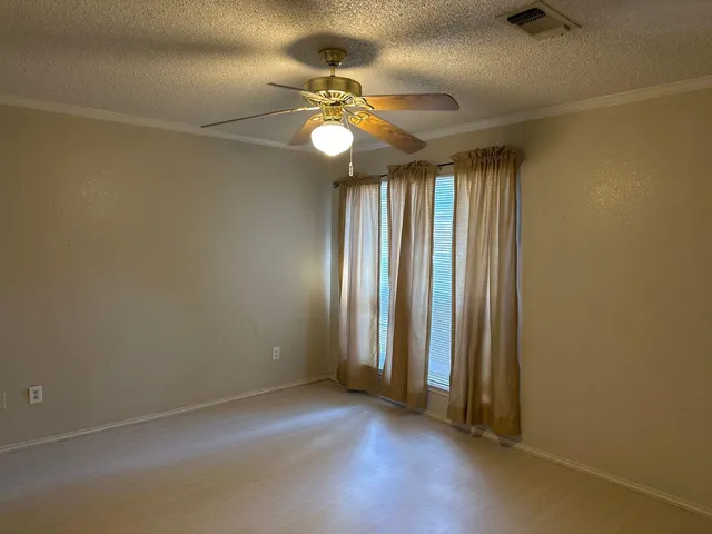 an empty room with windows and fan