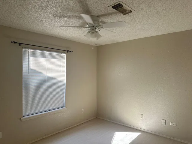an empty room with a ceiling fan and a window