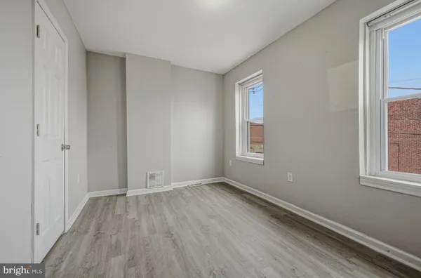 an empty room with wooden floor and windows