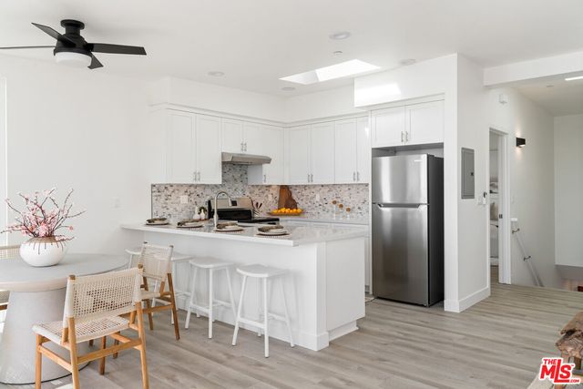 a kitchen with stainless steel appliances a refrigerator a stove a sink and white cabinets with wooden floor