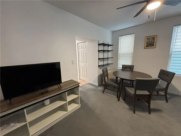a living room with furniture a flat screen tv and a window