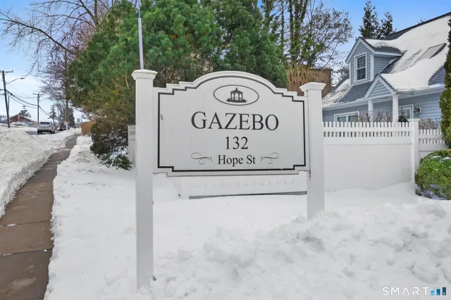 a view of a sign board with buildings in the background