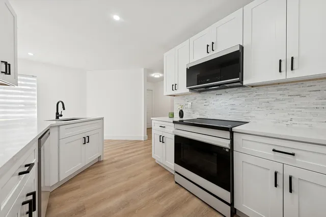 a kitchen with stainless steel appliances a stove microwave and sink