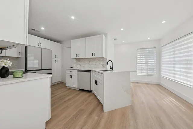 a kitchen with stainless steel appliances a white stove top oven cabinets and a wooden floor