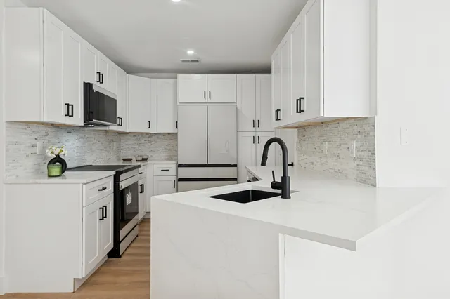 a kitchen with stainless steel appliances granite countertop a sink a stove and a refrigerator with wooden cabinets
