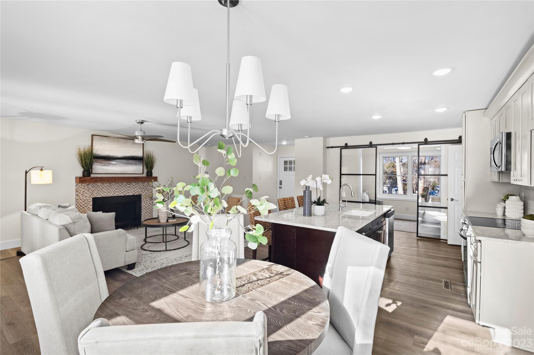 1621 Brook Drive Fort Mill, SC 29708 - Photo 5 of 30 a living room with fireplace furniture dining table a chandelier and a view of kitchen