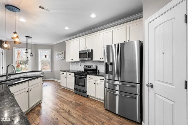 a kitchen with cabinets stainless steel appliances and wooden floor