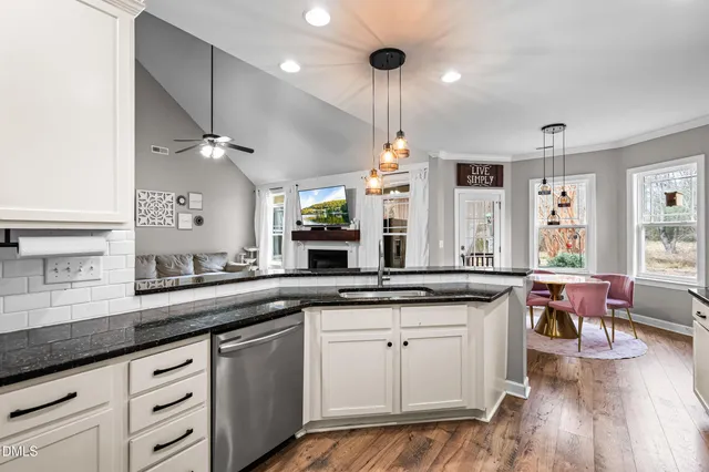a kitchen with granite countertop a sink a counter space appliances and cabinets