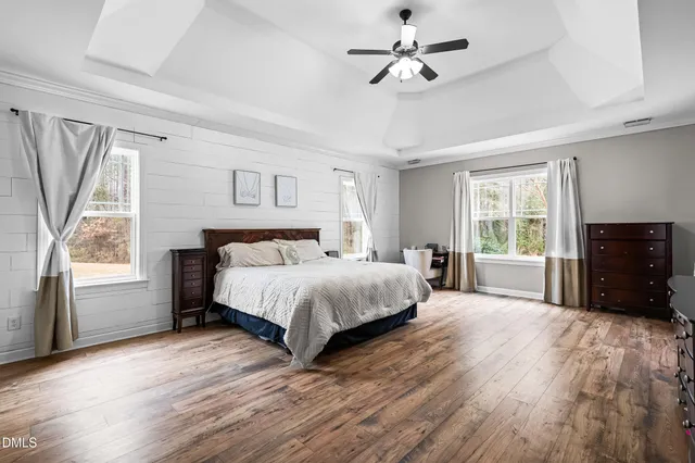a spacious bedroom with a bed a dresser and a chandelier