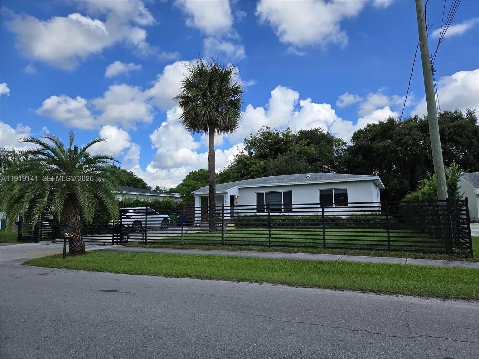 1269 Northeast 145th Street Miami, FL 33161 - Photo 2 of 25 a front view of a house with a garden and trees