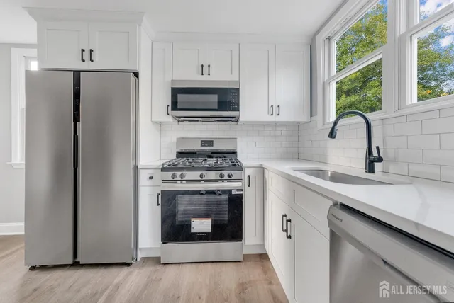 a kitchen with cabinets stainless steel appliances a sink and a window