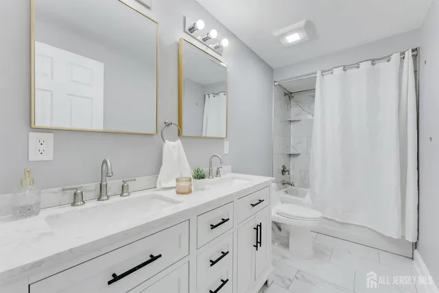 a bathroom with a double vanity sink toilet and shower