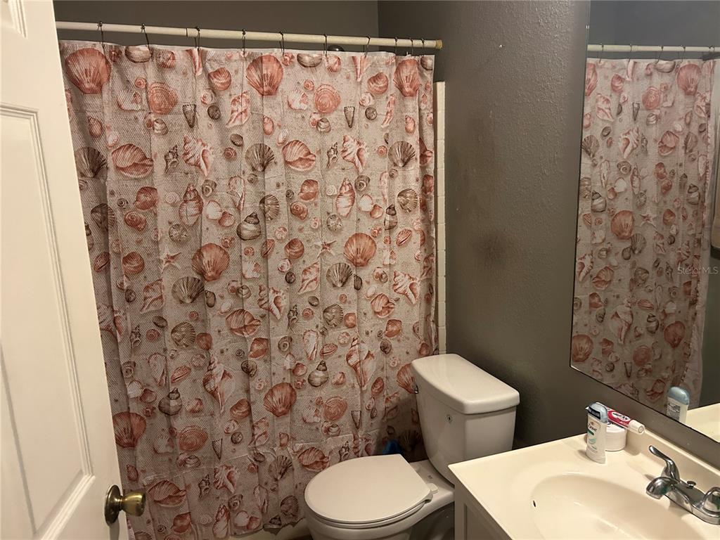 706 Hawk Lane Kissimmee, FL 34759 - Photo 7 of 9 a white toilet sitting next to a shower curtain