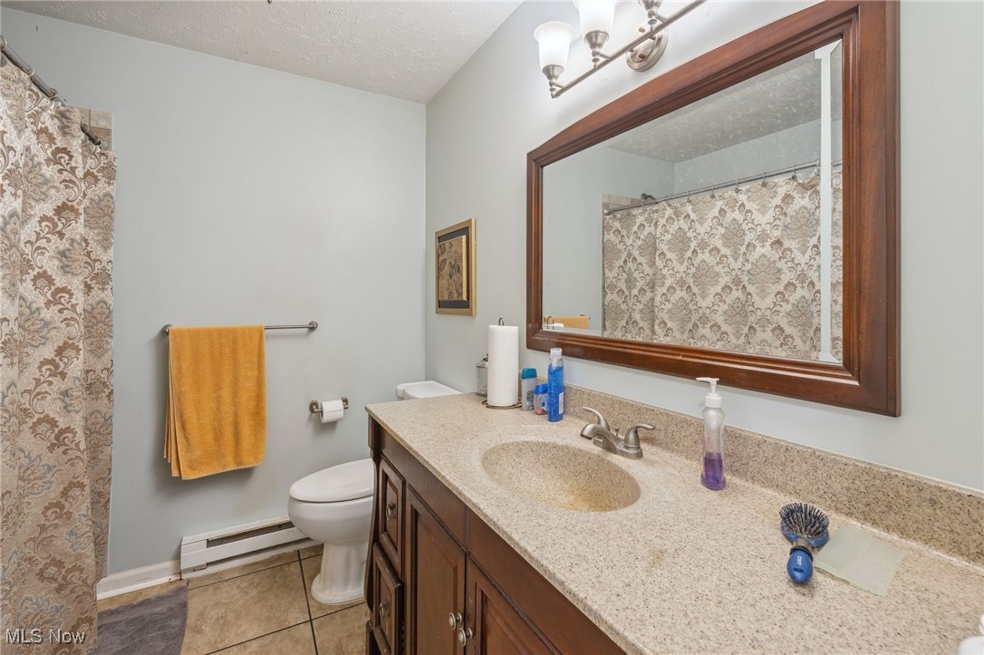 4790 Paradise Road Seville, OH 44273 - Photo 41 of 45 Full bath with vanity, a baseboard heating unit, toilet, a textured ceiling, and tile patterned floors