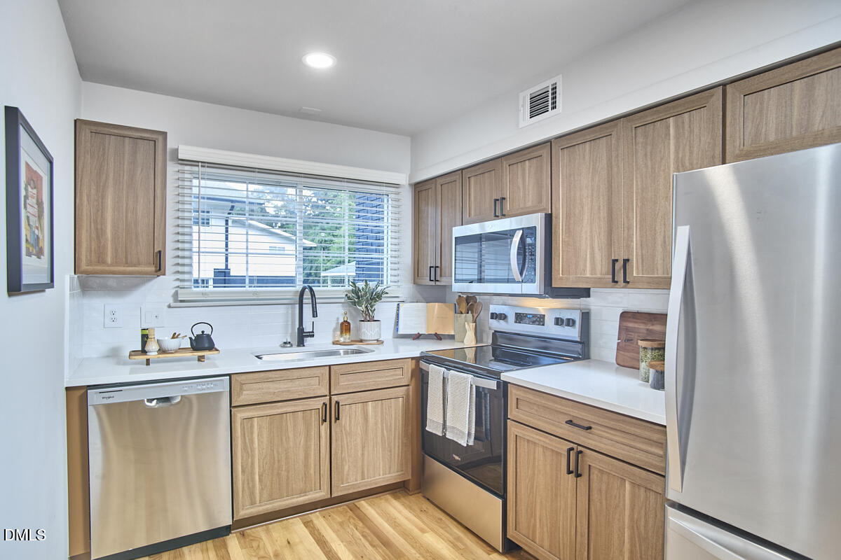 2613 McNeil Street, Unit B Raleigh, NC 27608 - Photo 16 of 31 a kitchen with a sink a refrigerator a window and cabinets