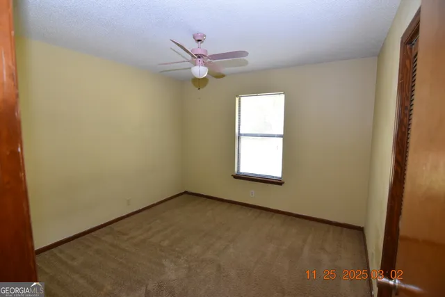 an empty room with a window and a fan