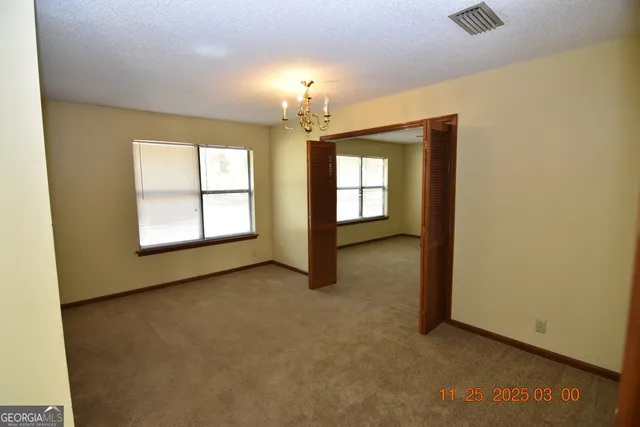 an empty room with windows and chandelier