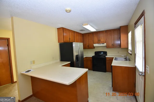 a kitchen with a refrigerator a stove top oven a sink and cabinets