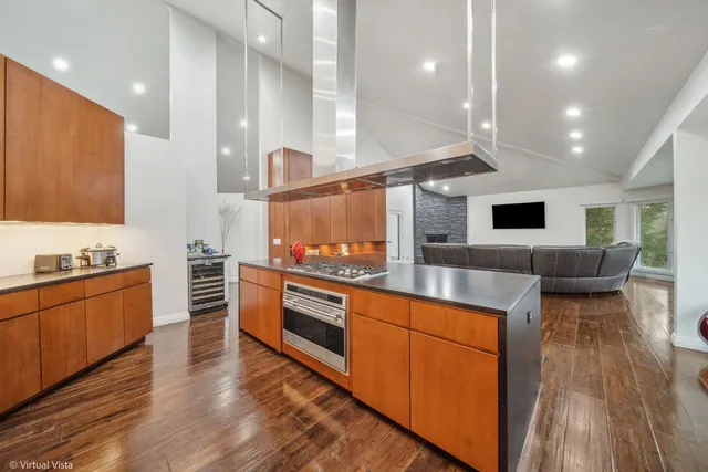 a kitchen with stainless steel appliances granite countertop a table chairs sink and wooden cabinets