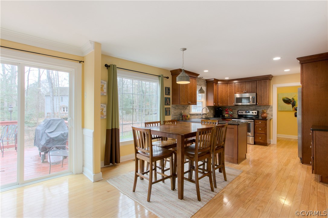 3310 Fortunes Ridge Road Midlothian, VA 23112 - Photo 11 of 29 a kitchen with stainless steel appliances kitchen island granite countertop a refrigerator a stove a sink a dining table and chairs with wooden floor