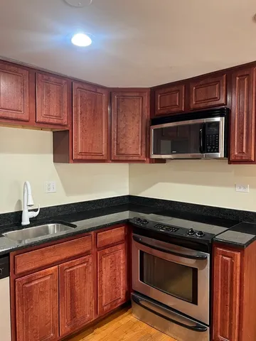 a kitchen with granite countertop a stove microwave and sink