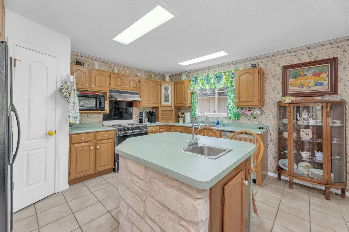 2105 Sam Bass Road Round Rock, TX 78681 - Photo 12 of 40 a kitchen with stainless steel appliances granite countertop a sink a stove and a refrigerator