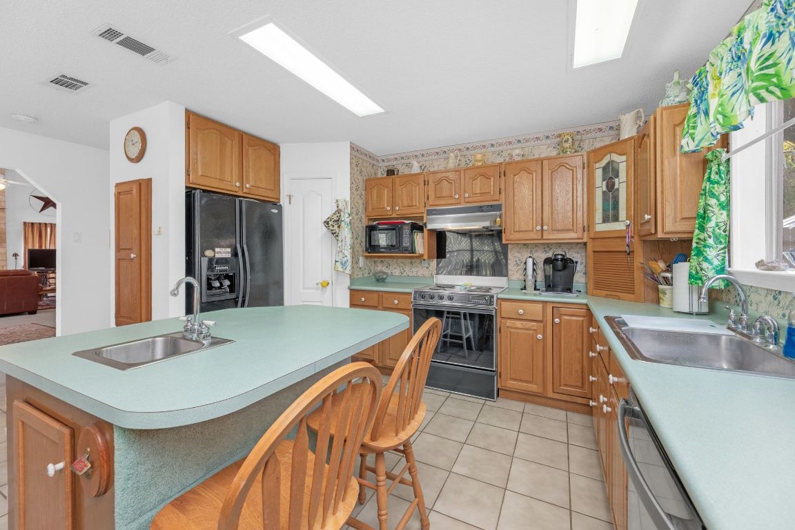 2105 Sam Bass Road Round Rock, TX 78681 - Photo 13 of 40 a kitchen with stainless steel appliances granite countertop a sink a stove a refrigerator cabinets and living room view