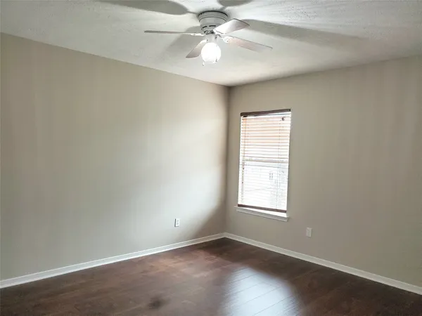 an empty room with windows and chandelier fan
