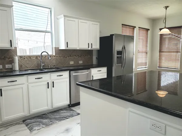 a kitchen with granite countertop a refrigerator and a sink