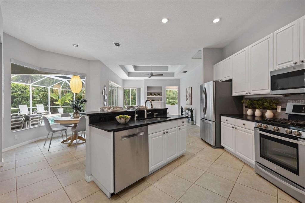 8204 Waterview Boulevard Lakewood Ranch, FL 34202 - Photo 22 of 77 a kitchen with stainless steel appliances granite countertop a stove top oven a sink dishwasher a refrigerator and white cabinets with wooden floor