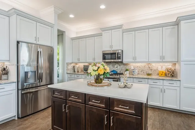 a kitchen with kitchen island granite countertop a refrigerator stove and white cabinets