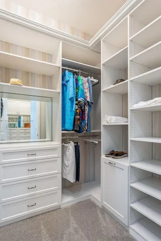 a view of walk in closet with clothes and shoes