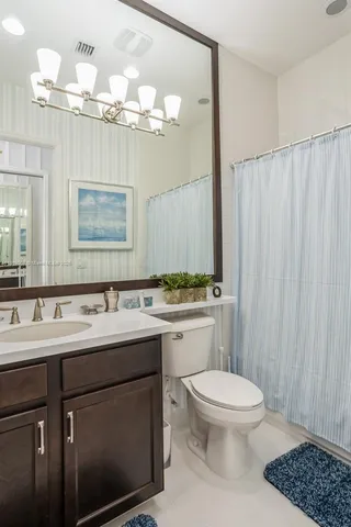 a bathroom with a toilet a sink a mirror a window and vanity