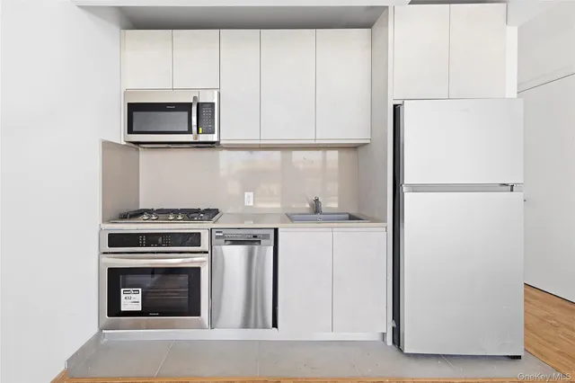 a kitchen with granite countertop white cabinets and stainless steel appliances
