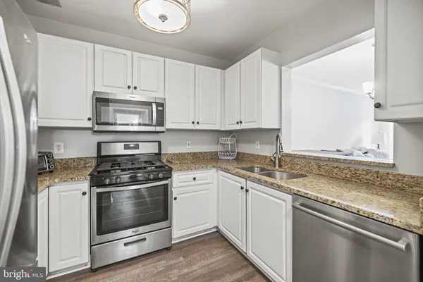 a kitchen with stainless steel appliances granite countertop a stove a sink and a microwave