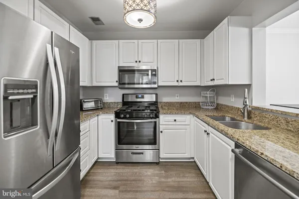 a kitchen with stainless steel appliances granite countertop a refrigerator sink and stove