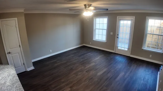 a view of an empty room with wooden floor and a window