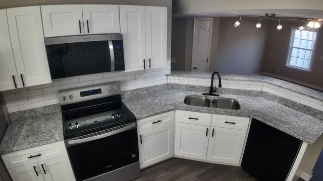 a kitchen with granite countertop a stove microwave and sink