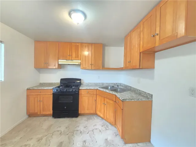 a kitchen with granite countertop a sink stove and cabinets