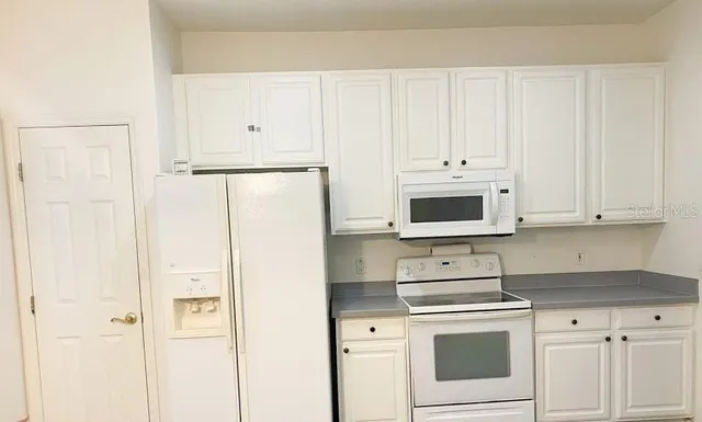 a kitchen with white cabinets and white appliances