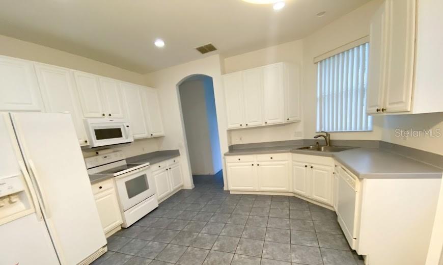 596 Neumann Village Court Ocoee, FL 34761 - Photo 6 of 25 a kitchen with granite countertop white cabinets and white appliances