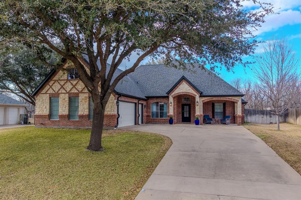 View of front of house featuring brick siding, a shingled roof, concrete driveway, covered porch, and an attached garage