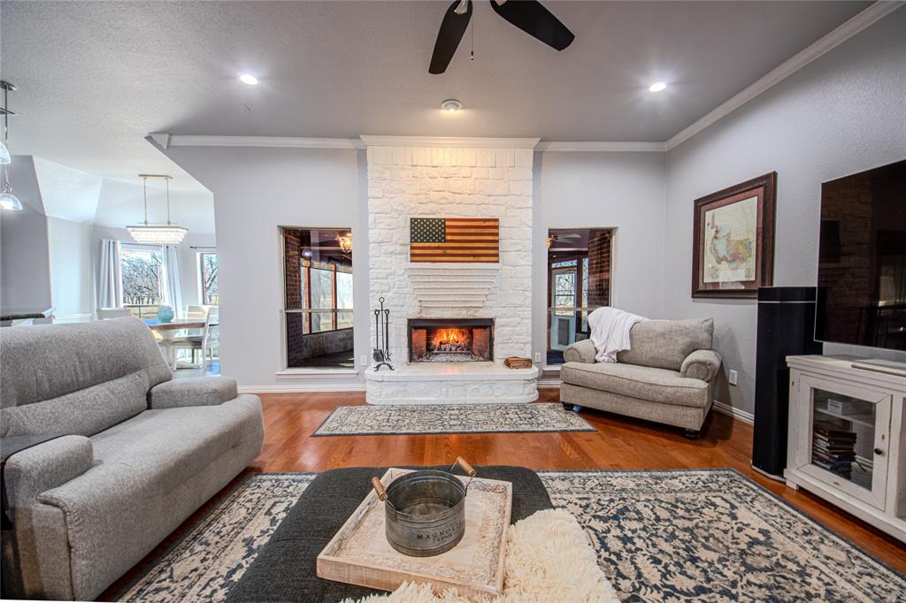 9001 Ravenswood Road Granbury, TX 76049 - Photo 11 of 38 Living area with ornamental molding, wood finished floors, a fireplace, and ceiling fan